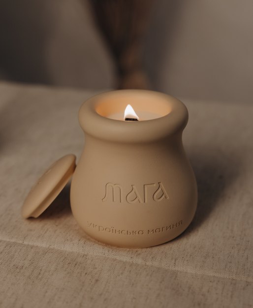 Lit MAGA candle in a handmade clay vessel