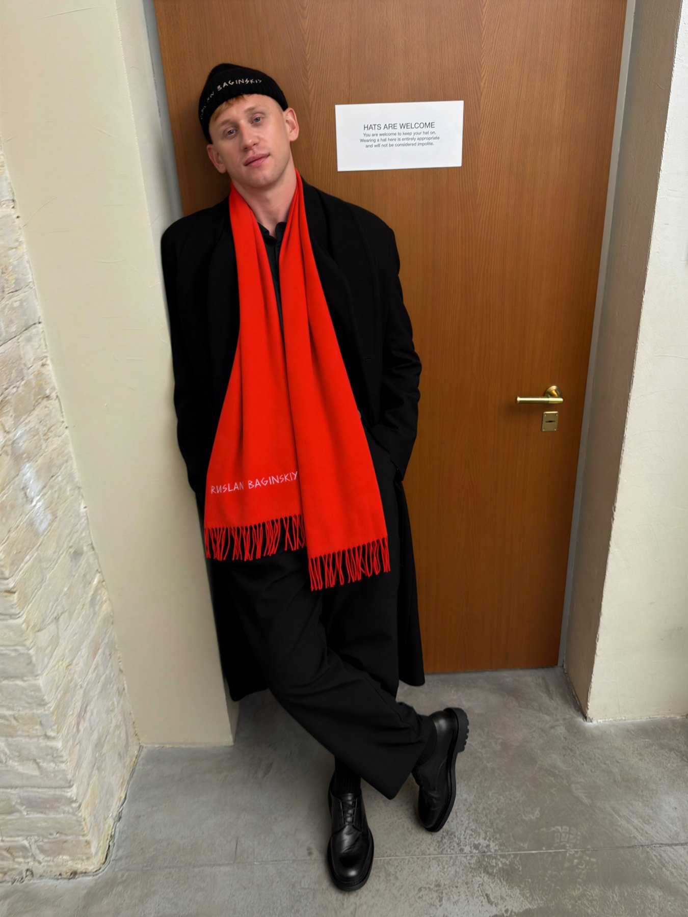 Model in a black beanie and long red scarf from the Fall 2026 lookbook